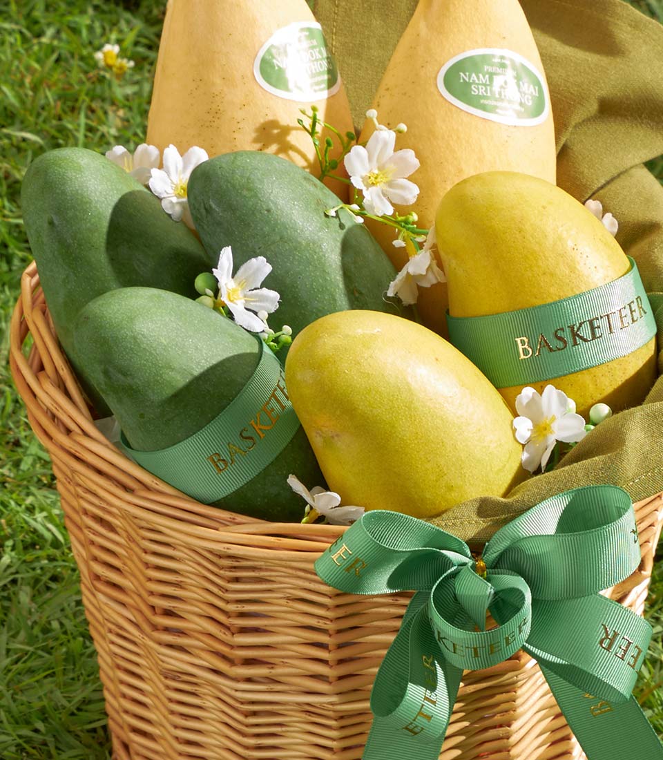 Premium Thai mango gift basket with woven wicker, fresh green and yellow mangoes, white flowers, and green silk bow