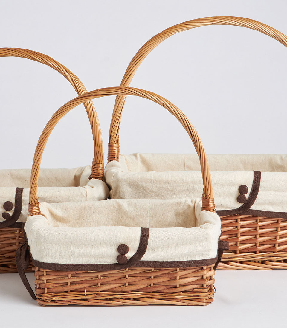 Handwoven rectangular wicker baskets with cream fabric linings and single handles, ready for luxury gift curation