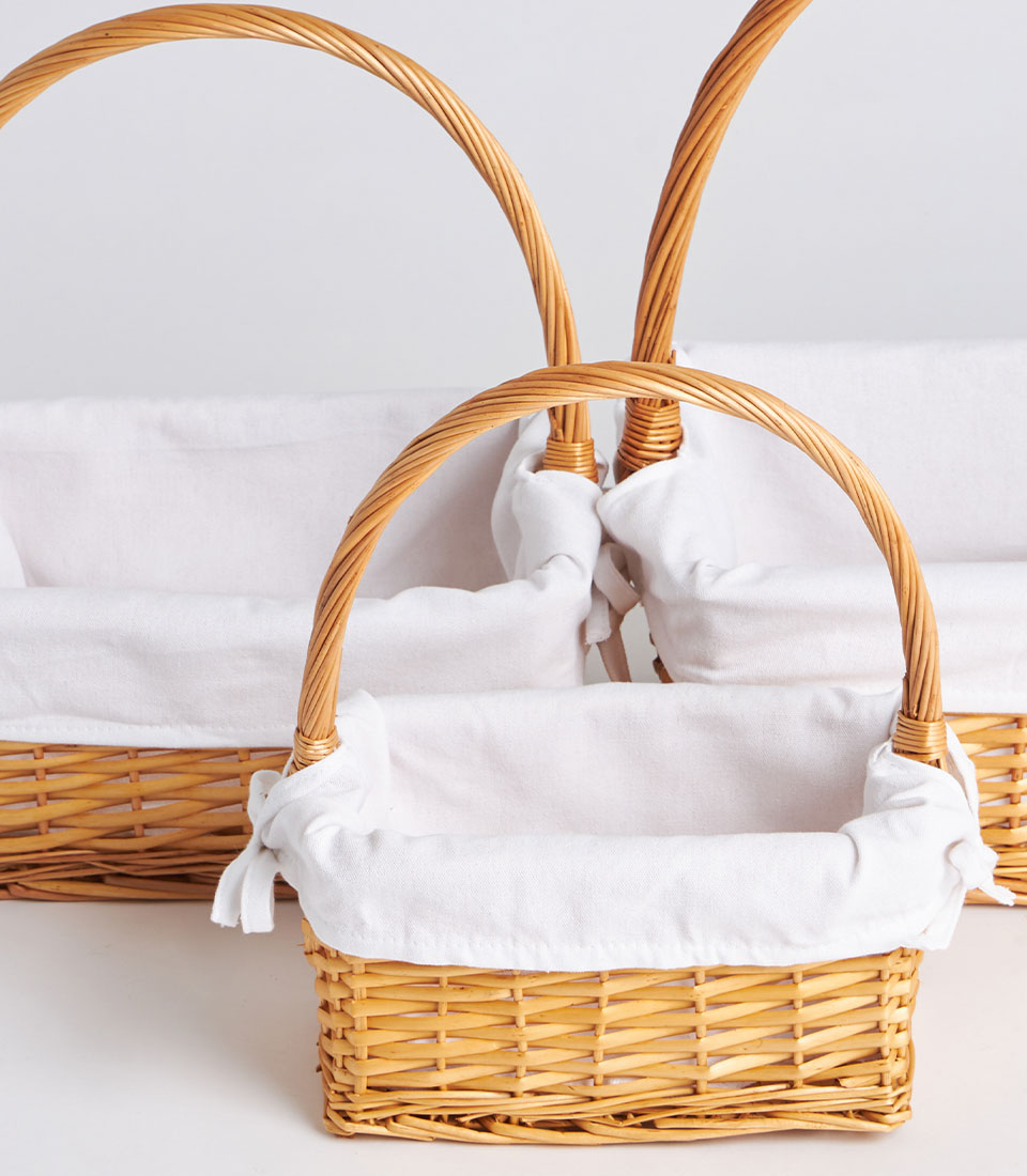 Handwoven light brown wicker gift baskets with white fabric linings and arched handles