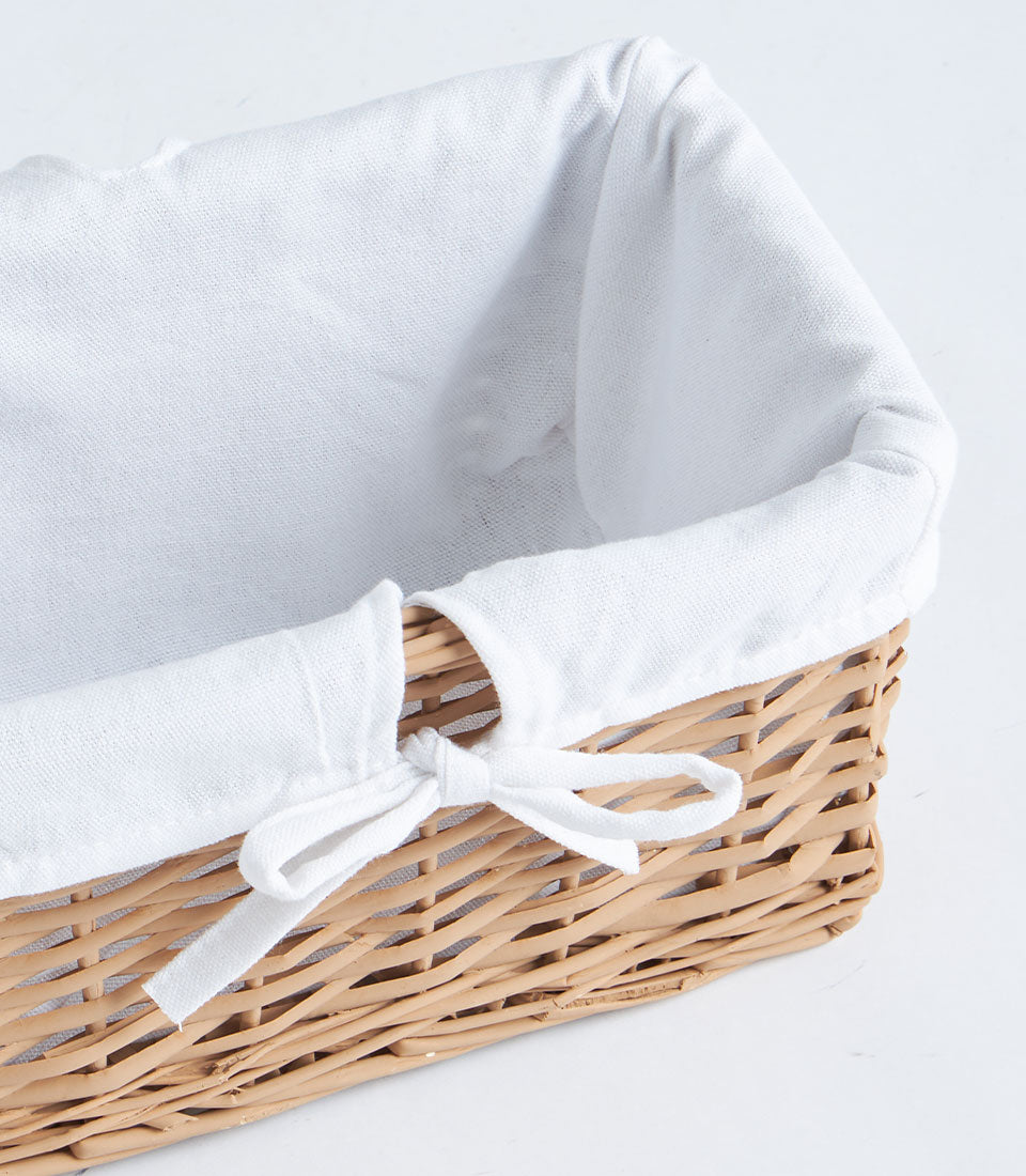 Natural wicker rectangular basket with white fabric lining and bow