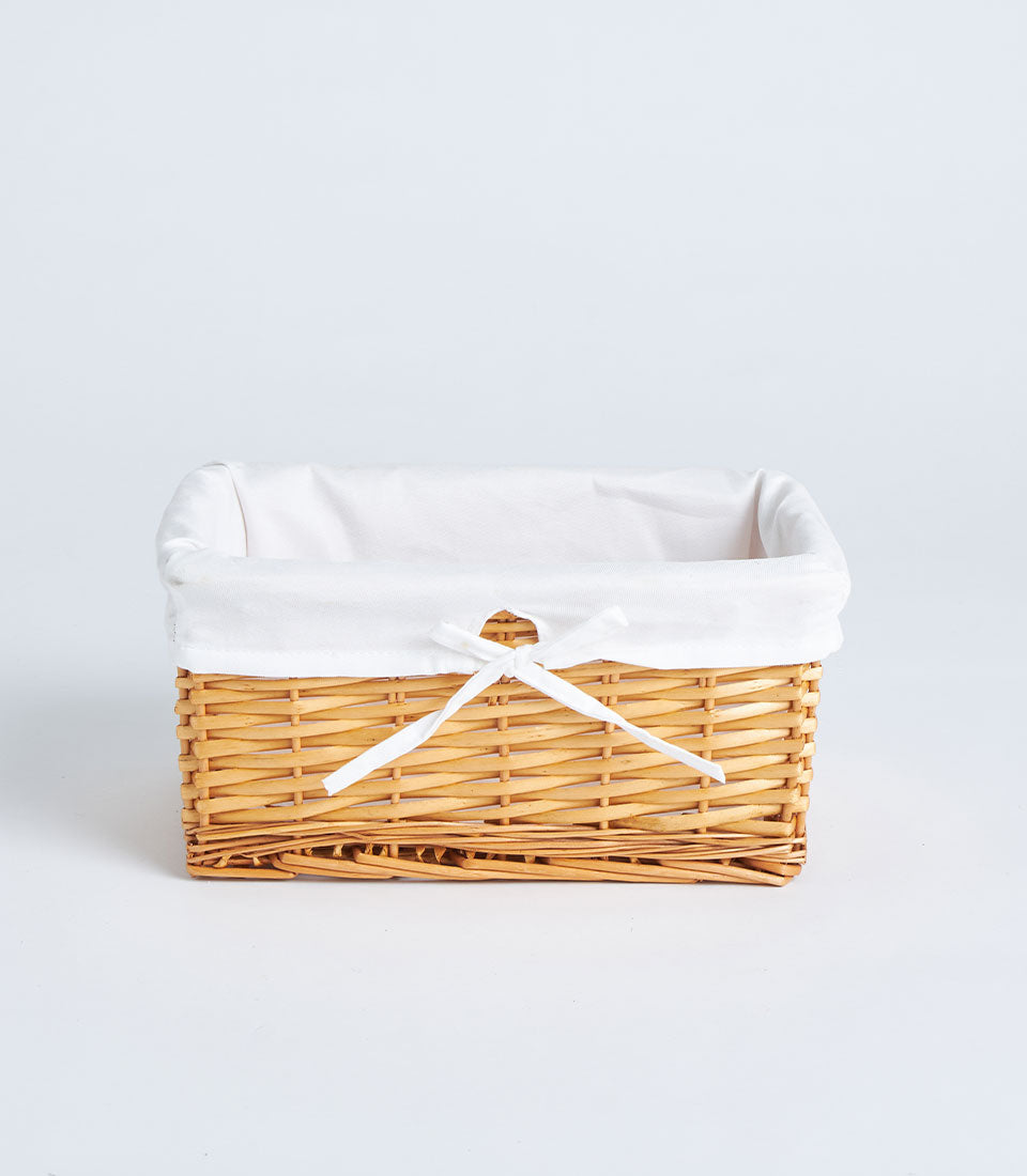 Handwoven rectangular wicker basket with white linen liner and ribbon tie