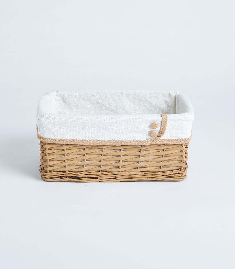 Light brown handwoven wicker basket with white linen liner and jute trim
