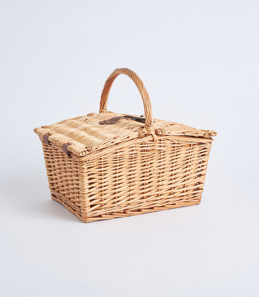 Light brown handwoven wicker picnic basket with leather straps and hinged lid