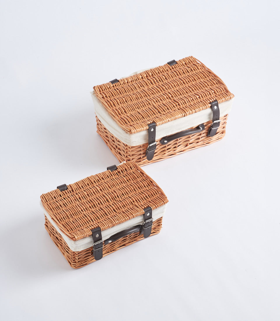Handwoven light brown wicker baskets with cream lining, leather straps, and silver buckles in two sizes