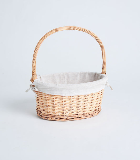 Light brown wicker gift basket with arched handle and beige fabric liner, tied with delicate bows