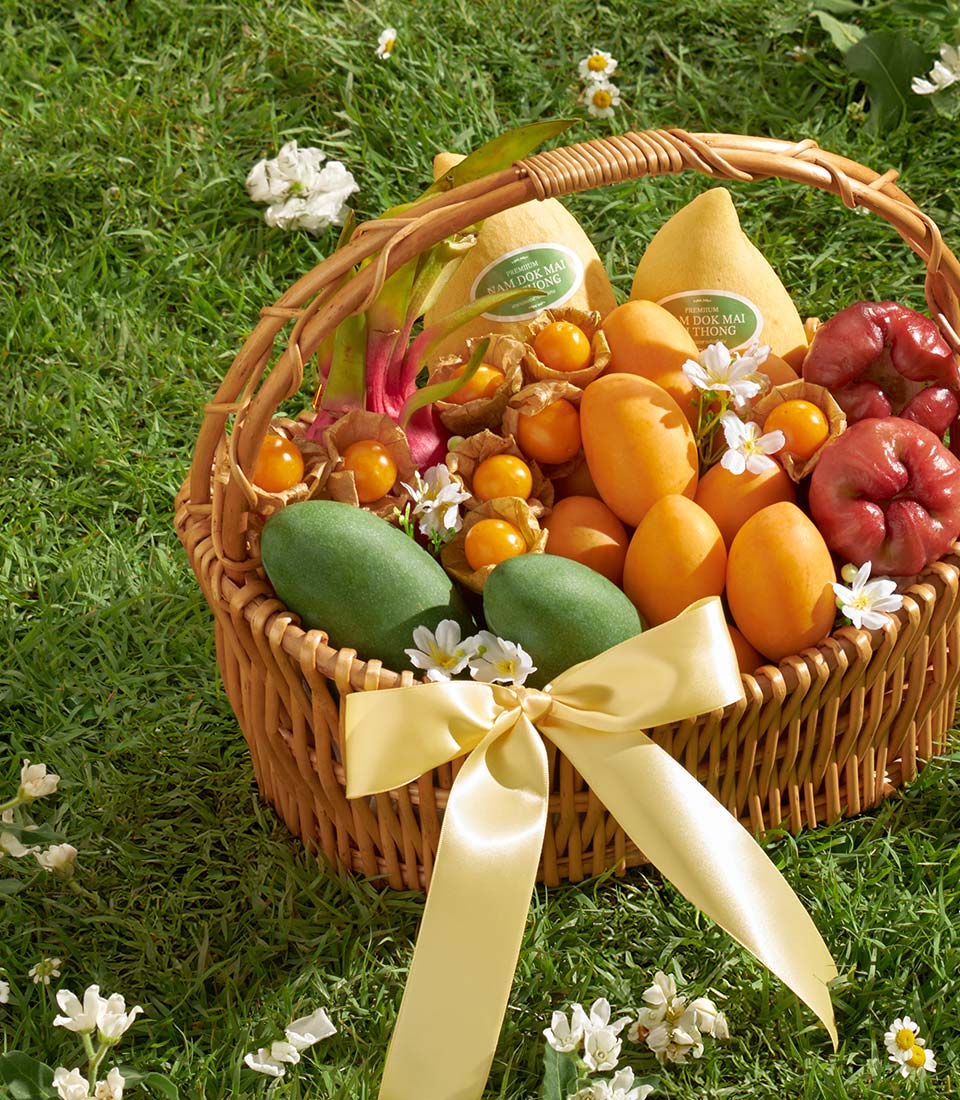 Premium tropical fruit basket with Nam Doc Mai mangoes, rose apples, and goldenberries in wicker with yellow ribbon