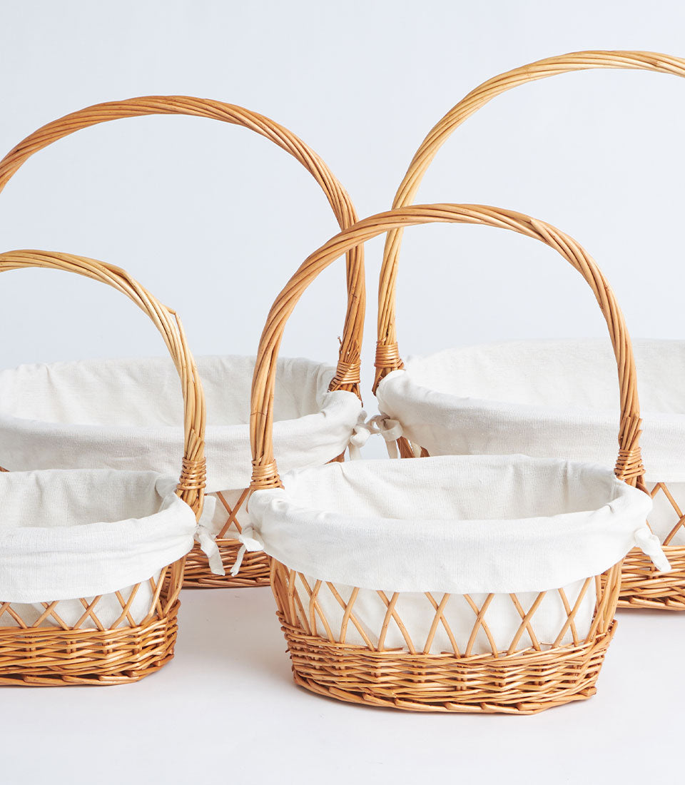 Natural wicker oval baskets with white fabric liners and arched handles, set of four