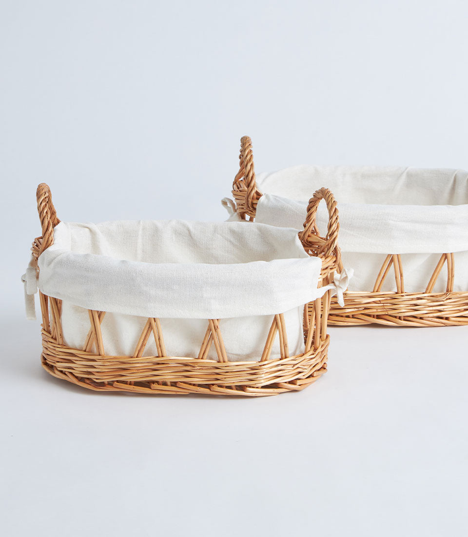 Light brown woven wicker baskets with white linen liners and braided handles for premium gift presentation