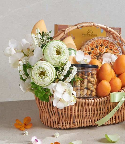 Woven wicker gift basket with white orchids, lotus flowers, fresh mangoes, gourmet pastries, roasted nuts, and Thai treats