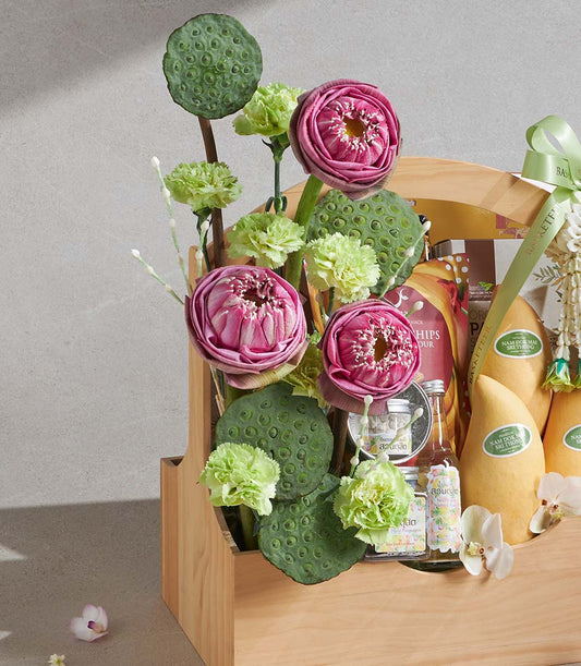 Songkran gift basket with pink lotus flowers, mangoes, gourmet snacks, and artisan provisions in natural wooden crate