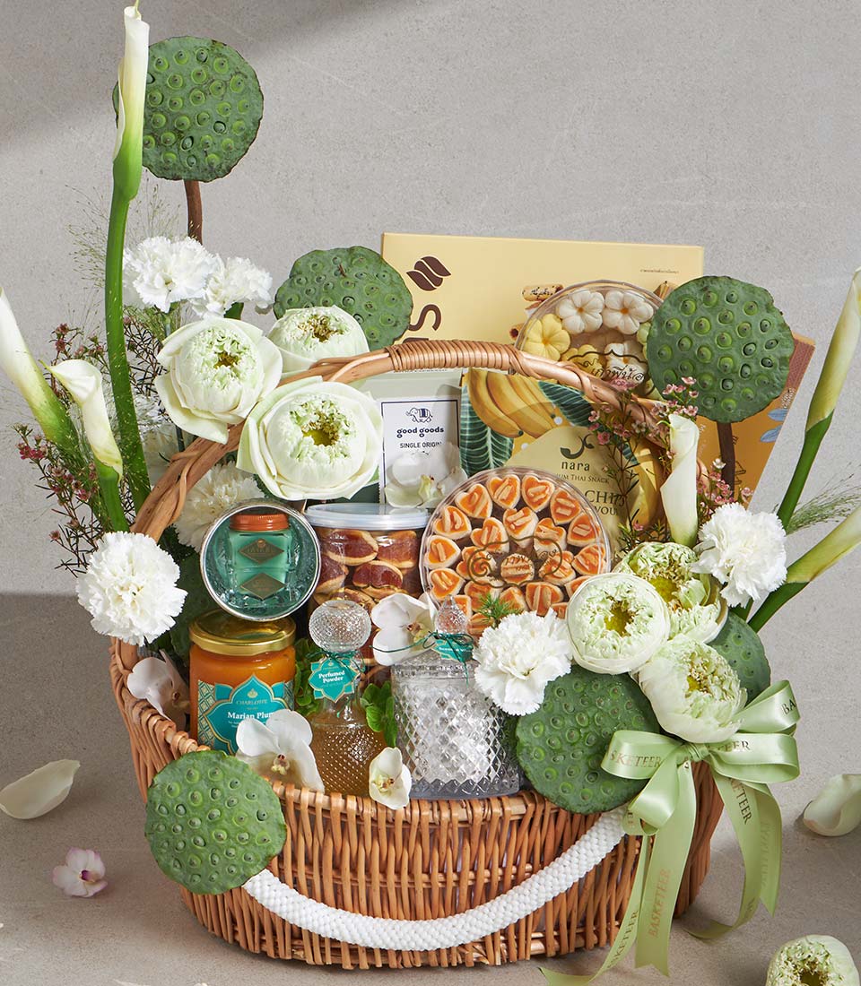 Luxury wicker gift basket with gourmet jam, pastries, candles, and fresh white lotus flowers with satin ribbon