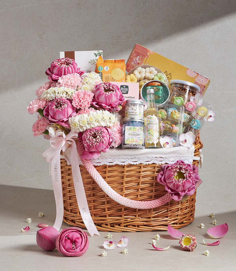 Large wicker gift basket with pink lotus flowers, gourmet snacks, artisan sweets, and premium toiletries for Songkran