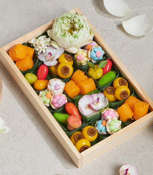 Thai lotus sweet dessert gift box with jasmine, orchids, and colorful traditional sweets in wooden compartments