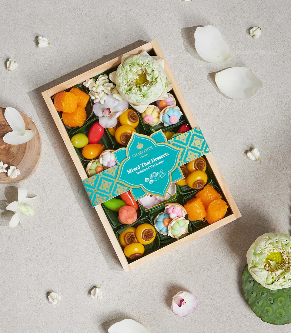Mini wooden box of assorted Thai lotus and traditional desserts with jasmine and orchid florals