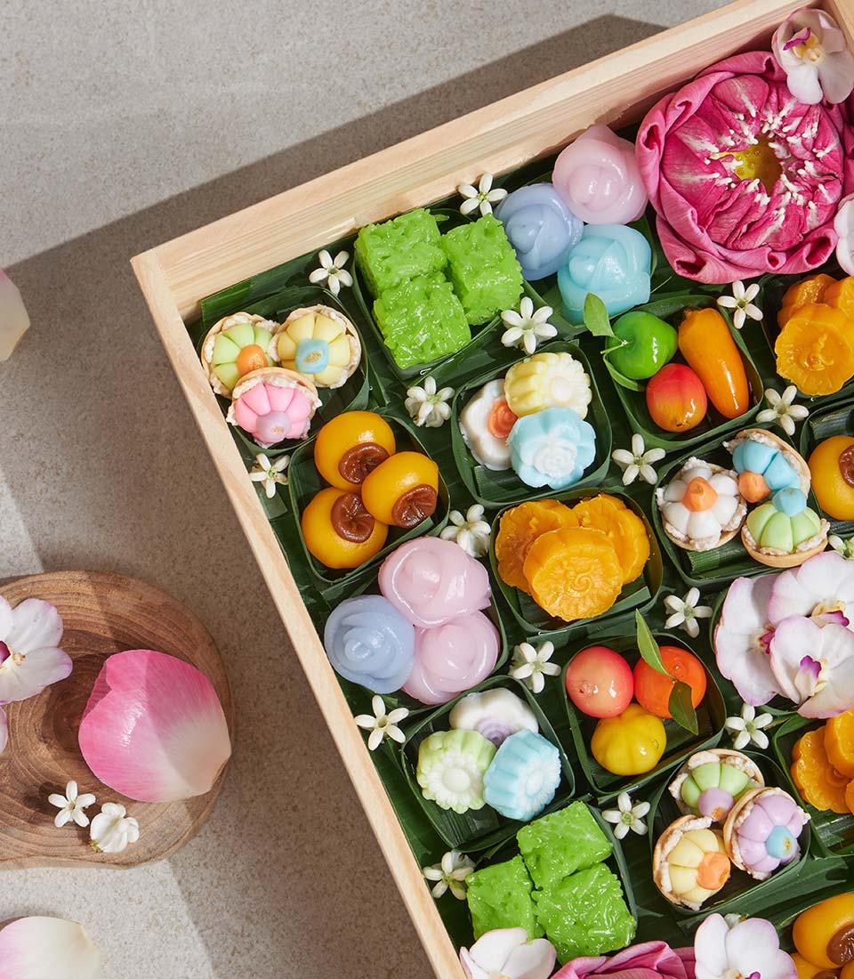 Thai lotus dessert gift box with colorful handmade sweets and jasmine flowers on banana leaves