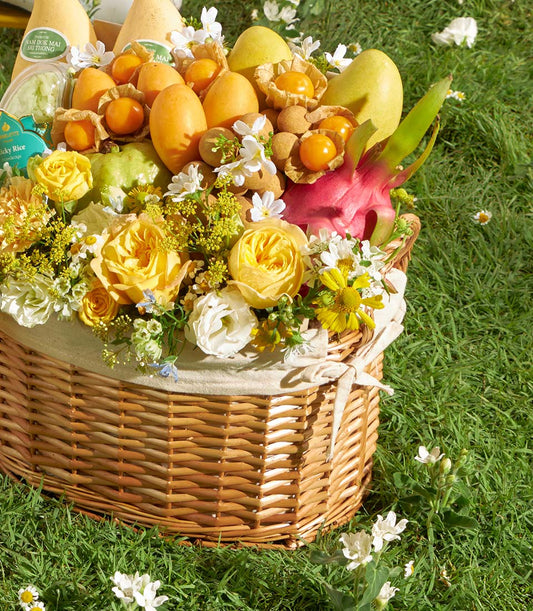 Summer Bloom wicker fruit basket with yellow mangoes, dragon fruit, and yellow roses
