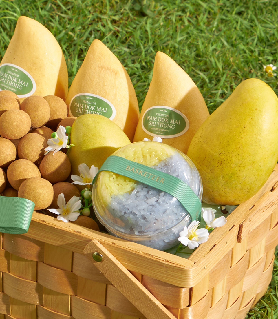 Wooden gift basket with premium Nam Dok Mai mangoes, longans, and two-tone sticky rice, tied with green Basketeer ribbon