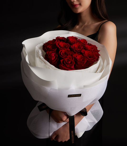 Lush red rose bouquet from Flowers by Basketeer, expertly wrapped in elegant white paper and tied with a logo ribbon. Perfect for flower delivery Bangkok.