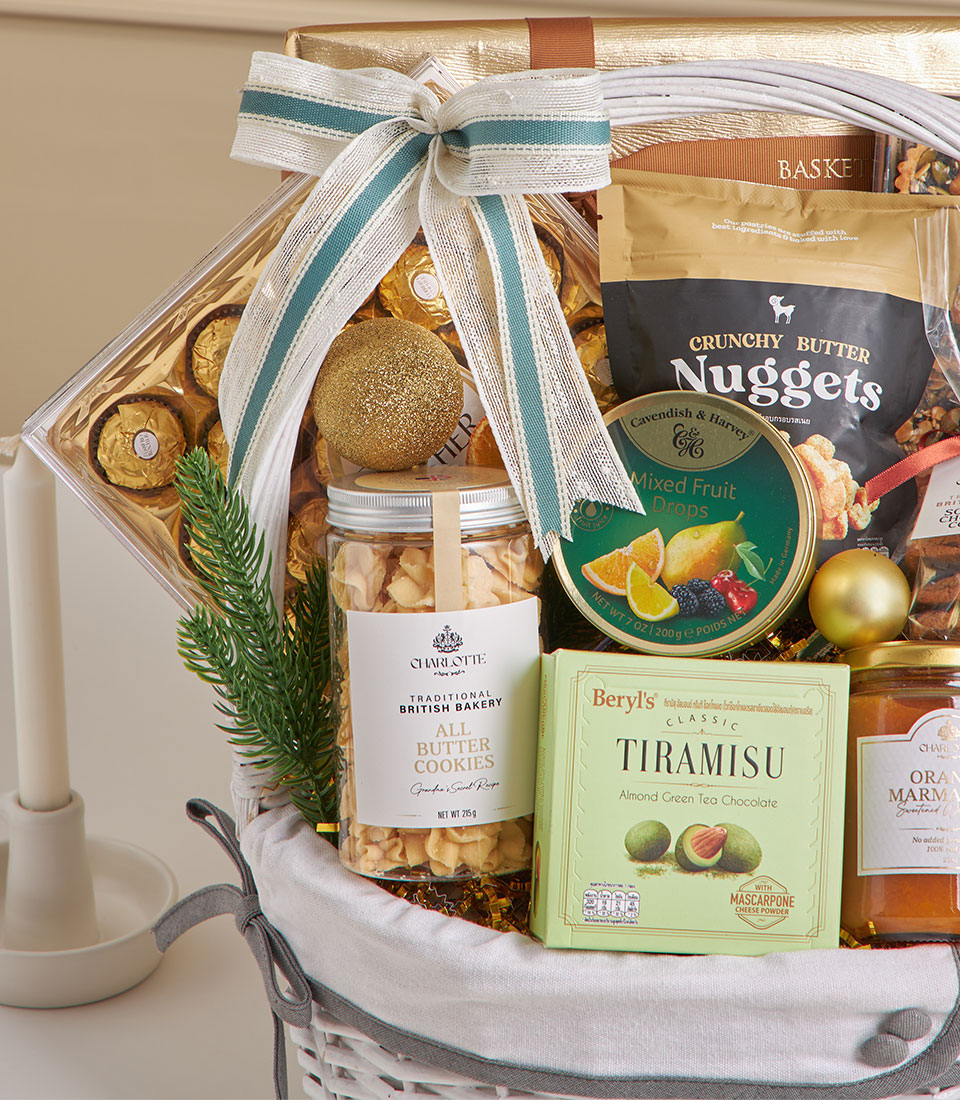 White wicker gourmet hamper with coconut roll, chocolate truffles, mixed nuts, and festive gold accents for New Year gifting