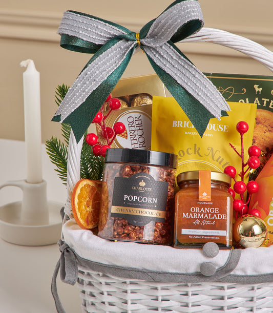 Premium gourmet gift hamper with chocolate chip cookies, popcorn and orange marmalade in white wicker basket, New Year