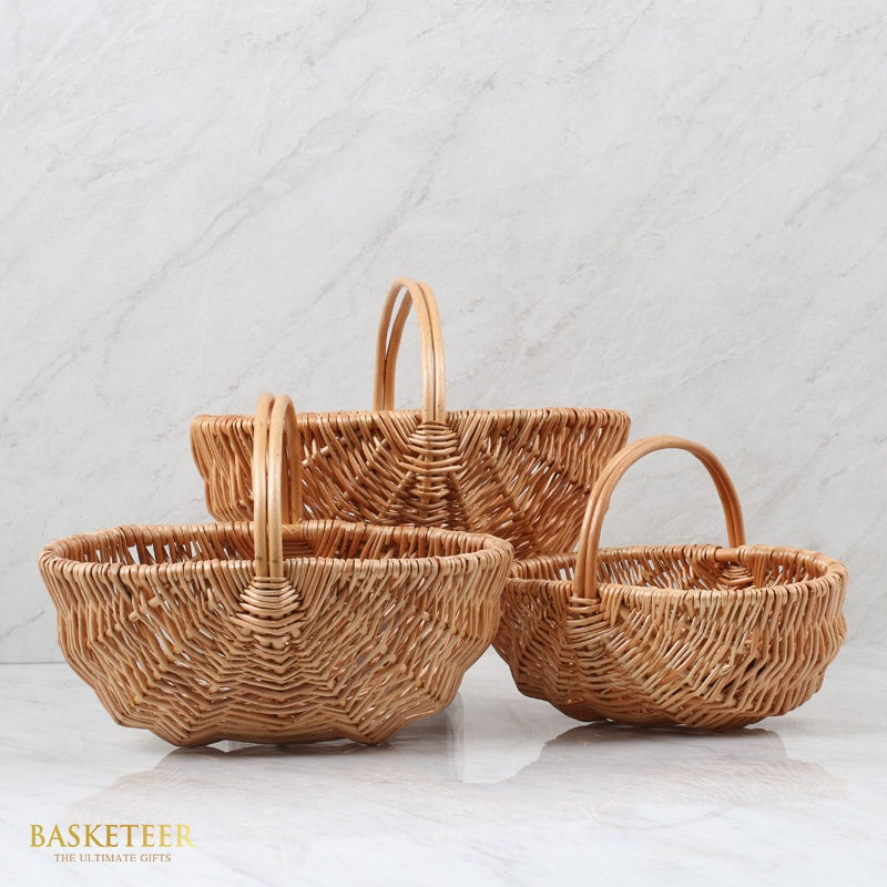 Light brown wicker baskets with handles in three graduated sizes, hand-woven natural rattan for artisan gift presentation