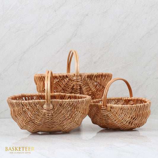 Light brown wicker baskets with handles in three graduated sizes, hand-woven natural rattan for artisan gift presentation