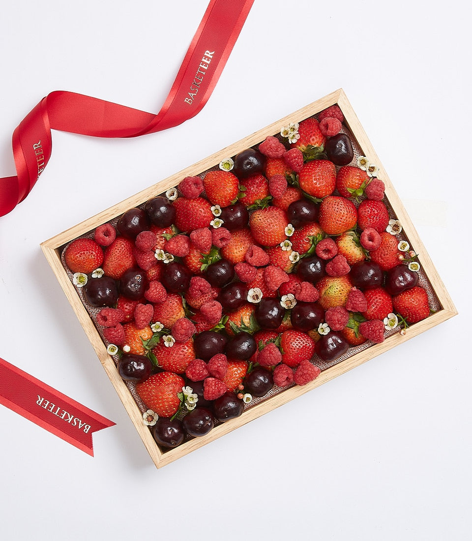 Mixed berry gift box with strawberries, cherries, and raspberries in wooden tray