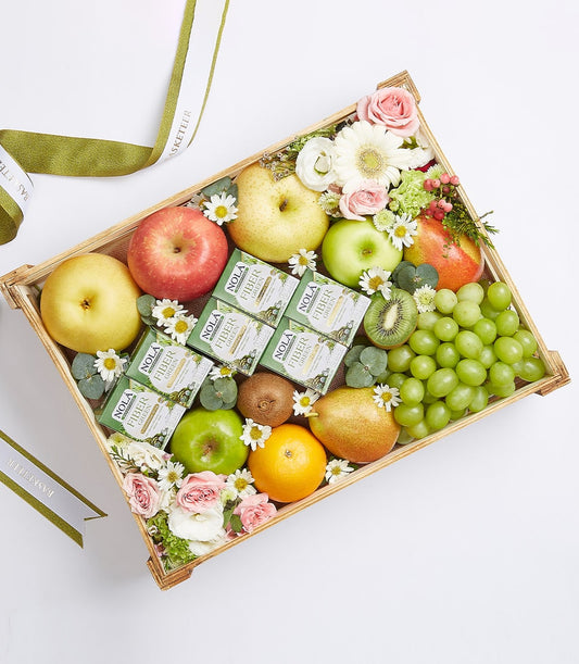 Wooden gift basket with fresh assorted fruits, fiber supplements, and mixed flowers with green ribbon