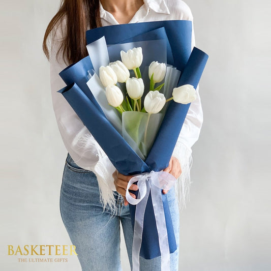 White tulips bouquet in navy and translucent wrap with white ribbon