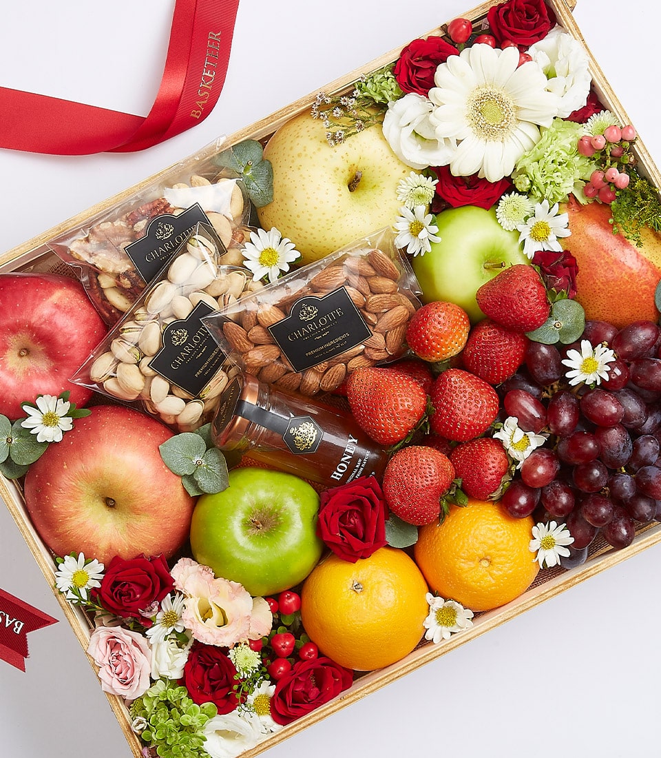Premium fruit and nut gift basket with fresh apples, pears, strawberries, artisan honey, and flowers in wooden crate