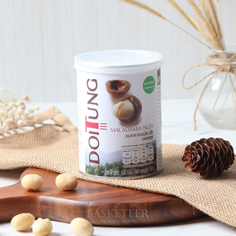 DoiTung natural macadamia nuts in white cylindrical can with scattered kernels on wooden board