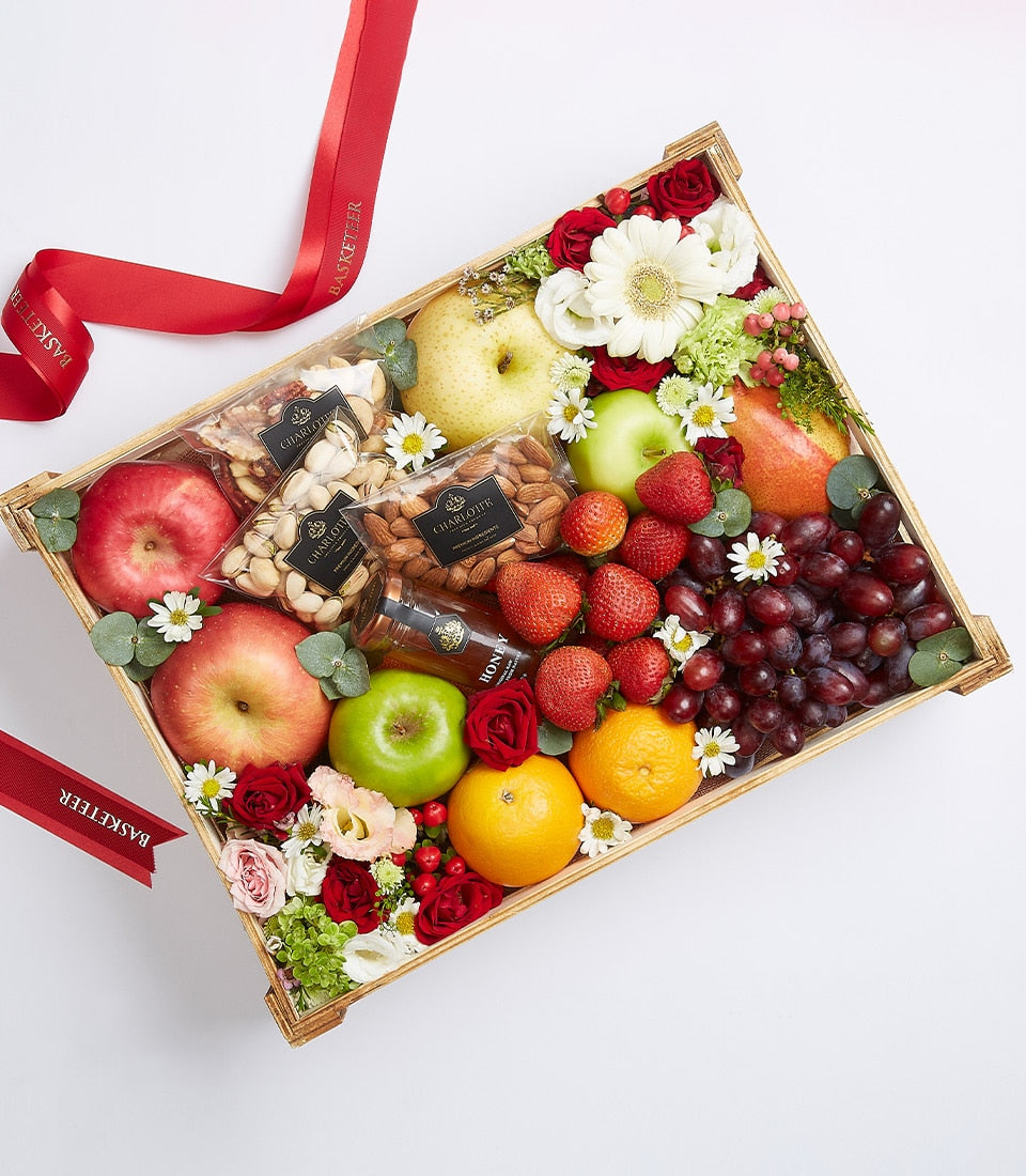 Luxury fruit and nut gift basket with apples, pears, grapes, strawberries, pistachios, almonds, honey, and fresh flowers