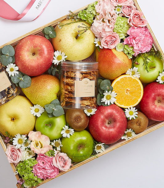 Exotic fruit gift box with apples, pears, kiwis, pink roses, carnations, hydrangeas, and gourmet snacks in wooden crate