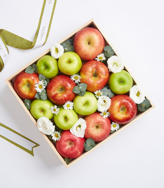 Premium wooden gift box with fresh red and green apples, white flowers, and eucalyptus accents