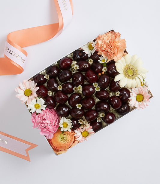 Dark red cherries and fresh peach carnations in an elegant gift box with cream gerbera daisy
