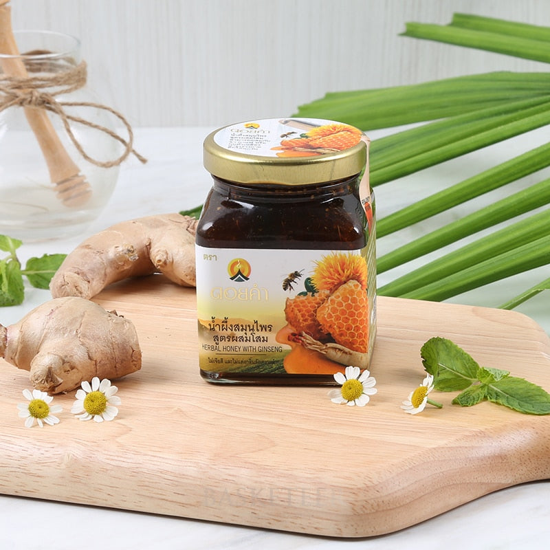 Premium herbal honey with ginseng in gold-topped jar, surrounded by fresh ginger, mint, and daisies on wooden board
