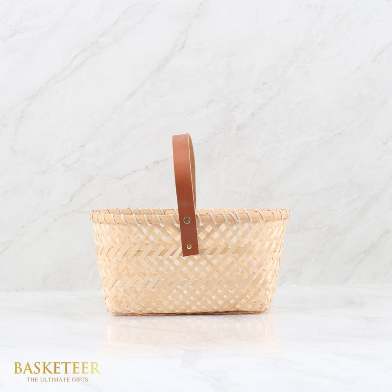 Light bamboo woven basket with brown leather handle and gold rivets, luxury gift hamper by Basketeer