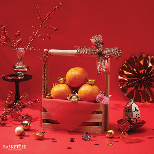 Lunar New Year mandarin gift basket with gold ingots, red tissue, and festive decorations on wooden crate