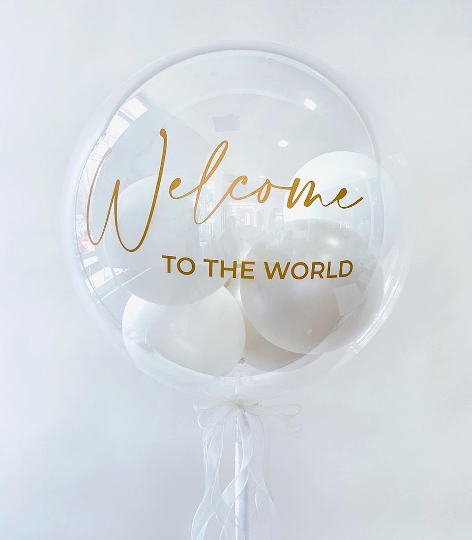 Shimmering gold "Welcome to the World" bubble balloon with nested white balloons and white ribbon bow