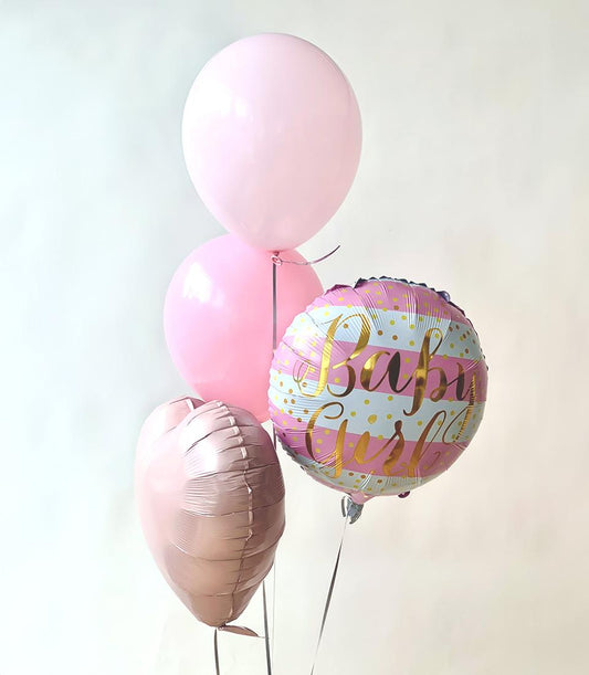 Light pink and rose gold baby girl balloon bouquet with striped foil balloon and polka dot accents