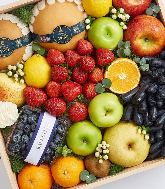 Wooden gift box filled with fresh pears, strawberries, apples, oranges, grapes, and blueberries with white foam cushioning