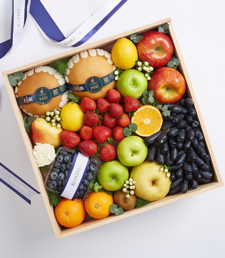 Wooden fruit hamper with pears, apples, berries, grapes, and citrus nestled in burlap with eucalyptus