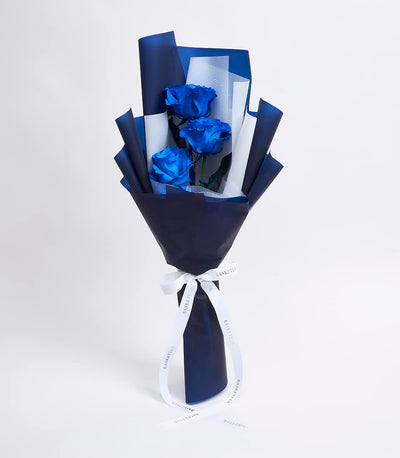 Royal blue roses with water droplets in navy and white wrapped bouquet with white ribbon bow