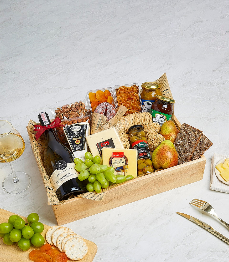 Gourmet wine and cheese hamper with brie, cheddar, olives, preserves, nuts, and dried fruit in wooden tray