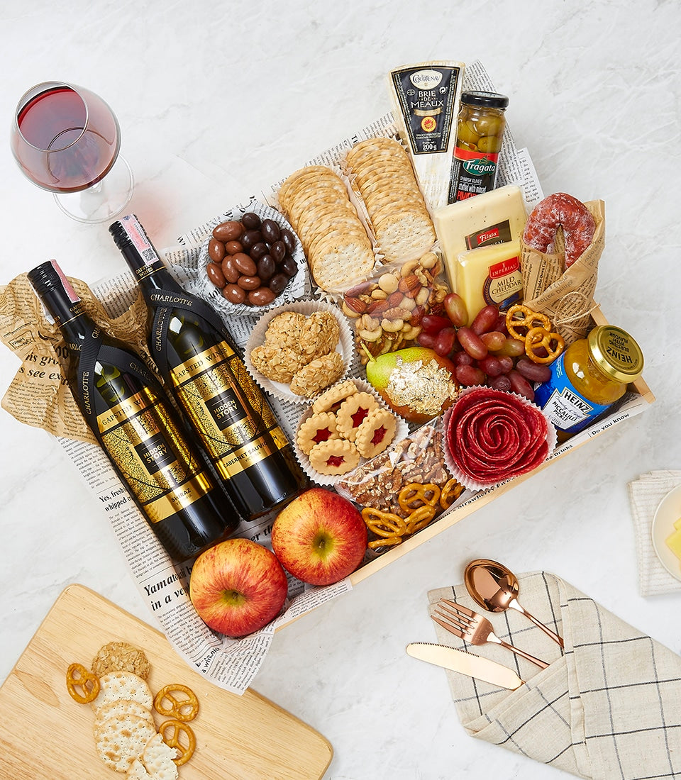 Premium wine and gourmet hamper with red wines, artisan cheeses, charcuterie, and crackers in wooden tray