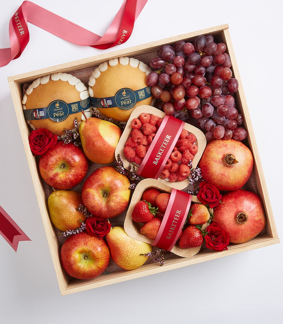 Luxury wooden gift box with fresh pears, grapes, pomegranates, apples, raspberries, strawberries, and roses