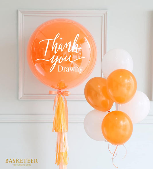 Orange and white balloon bouquet with personalized bubble balloon and tissue paper tassel for birthday celebrations