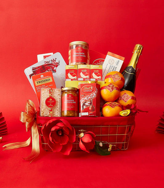 Festive red and gold wire gift basket with sparkling wine, oranges, chocolates, and gourmet treats for Chinese New Year