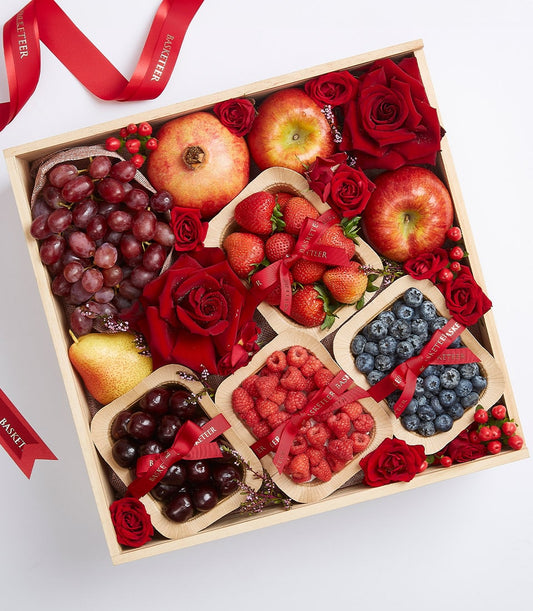 Wooden gift box with mixed fresh fruits, berries, pomegranate, red roses and red satin ribbons