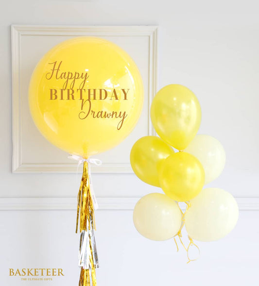 Yellow Happy Birthday balloon with gold and silver tassel garland and cream tone balloon cluster
